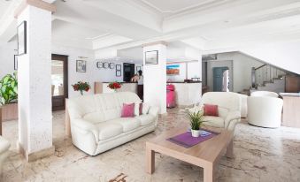 a living room with a white couch , a coffee table , and a kitchen in the background at Manolya Hotel