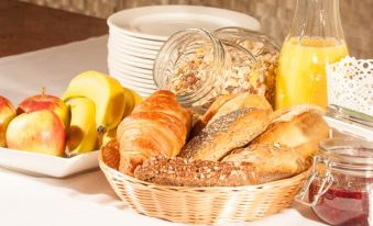 a wicker basket filled with various types of bread , including croissants , bagels , and rolls , placed on a dining table at LUDWIGS