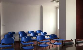An empty classroom is depicted, featuring blue chairs and a whiteboard positioned on the wall at one end at Yuhang Hotel