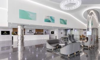 a modern hotel lobby with white walls , gray marble floors , and a large chandelier hanging from the ceiling at Meriton Suites Southport