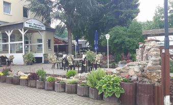 an outdoor dining area with tables and chairs set up in a courtyard , surrounded by greenery at Hotel Waldhaus