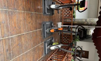 three exercise bikes are lined up on a wooden deck , with one of them having an orange handle at Panda Hotel