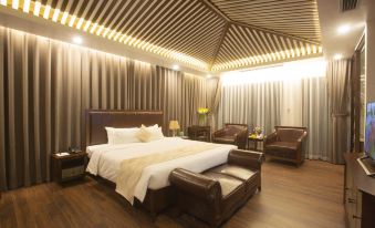 a large bed with white linens is in a room with brown leather chairs and striped ceiling at Westlake Hotel & Resort Vinh Phuc