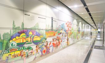 There is a mural featuring children's art on the wall of an airport, along with additional seating areas at Guangzhou Baiyun Airport Passenger Time Lounge (T1 Terminal Store)