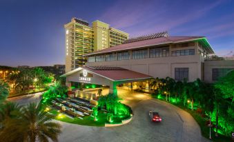 a large hotel with a red and green color scheme , surrounded by palm trees and lit up at night at Sanya Xizang Hotel