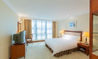 The bedroom is equipped with a large bed, desk, and chair positioned in front of the window at Metropark Hotel Shenzhen