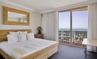 a hotel room with a large bed and a view of the ocean through a sliding glass door at Mantra Mackay