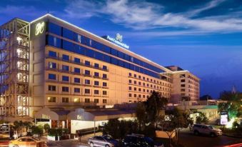 a large , modern hotel building with a blue and white exterior , illuminated at night , surrounded by traffic lights and cars at Pearl Continental Hotel Malam Jabba