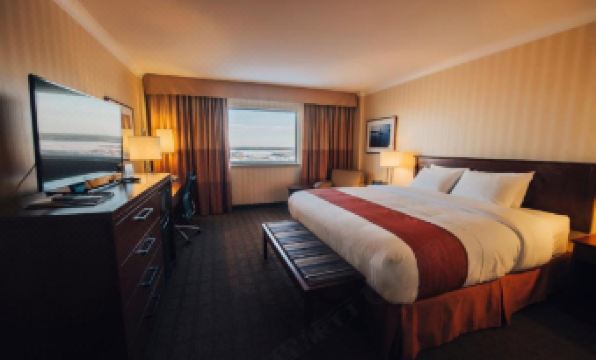 a well - lit hotel room with a large bed , desk , and window , providing a comfortable stay for guests at The Explorer Hotel