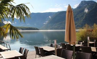 a serene outdoor dining area overlooking a body of water , with umbrellas and tables set up for guests at Seehotel Grüner Baum