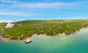 a bird 's eye view of a resort nestled in the middle of a lush green forest and clear blue water at Hotel Las Islas