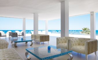 a large , modern living room with multiple couches and chairs , all facing the ocean at Grecotel Lux.ME White Palace