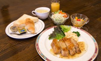 a wooden dining table with a plate of food , a cup of juice , and various utensils at Sun Palace Hotel