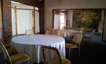 a large dining room with several round tables covered in white tablecloths and chairs arranged around them at Charlton Motel