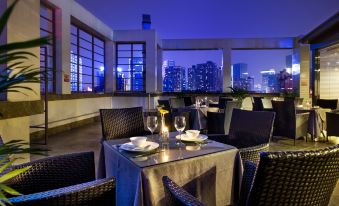 The dining room features a table and chairs with a view of the city at night from inside the restaurant at Howdy Smart Hotel (Chengdu Chunxi Taikoo Li)