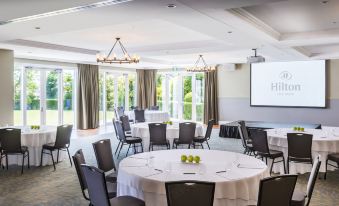 a conference room set up for a meeting , with several tables and chairs arranged in a circle at Hilton Lake Taupo