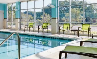 an indoor swimming pool surrounded by chairs and umbrellas , providing a relaxing atmosphere for guests at SpringHill Suites Oklahoma City Downtown/Bricktown