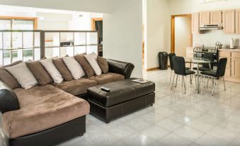 a modern living room with a brown leather couch , a dining table , and a kitchen area at Roxbury Suites