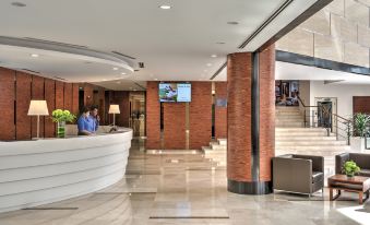 a hotel lobby with a marble floor , a white reception desk , and a staircase leading to the second floor at Oakwood Hotel & Residence Kuala Lumpur