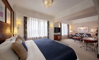 a large bed with a blue blanket is in the center of a room with two lamps and a chandelier at Hotel Royal