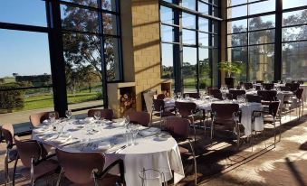 a large dining room with several tables and chairs arranged for a group of people to enjoy a meal together at Aitken Hill