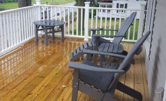 a wooden deck with two chairs , one of which is gray , and a white railing at Devils Lake Inn