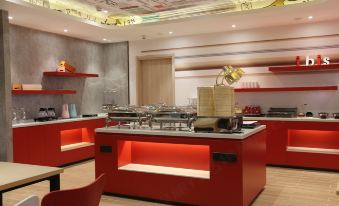 a modern kitchen with red cabinets , a gold sink , and various utensils on the counter at Ibis Hotel (Harbin Museum Subway Station)
