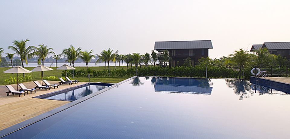 a large swimming pool with a building in the background and trees surrounding the area at Duyong Marina & Resort