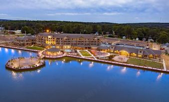 an aerial view of a large hotel surrounded by water , with the hotel lit up at night at Chautauqua Harbor Hotel - Jamestown