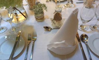 a dining table set for a formal dinner , with multiple place settings and utensils arranged neatly at Uplawmoor