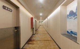 There is a long carpeted hallway with a door leading to another room in an empty hallway at Discovery Hotel (Guangzhou Railway Station Sanyuanli Subway Station)