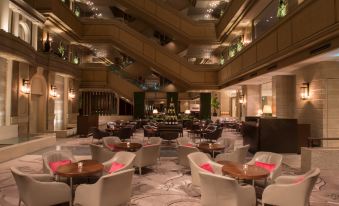 a luxurious hotel lobby with white furniture , green and red lights , and a staircase leading to the upper floors at Nagoya Tokyu Hotel