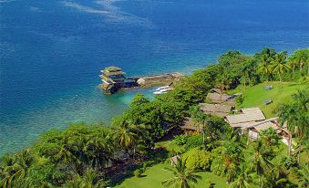 aerial view of a tropical island with lush greenery , a small island in the distance , and a body of water at Janji Laut Resort