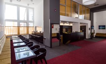 a modern hotel lobby with a red carpeted floor and several chairs arranged around a dining table at Hotel 99