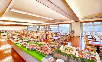 a large dining room with a long buffet table filled with various food items , such as fruits , vegetables , and desserts at Nagasaki Nisshokan