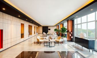 a modern , well - lit room with white walls and black floor tiles , containing several chairs and tables arranged in the center at Ibis Styles Bekasi Jatibening