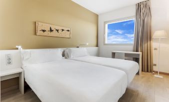 a hotel room with two white beds , one on the left and one on the right side of the room at B&B Hotel Barcelona Viladecans
