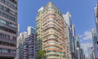 An intersection in a city with tall buildings and people walking on the sidewalk at Check Inn HK