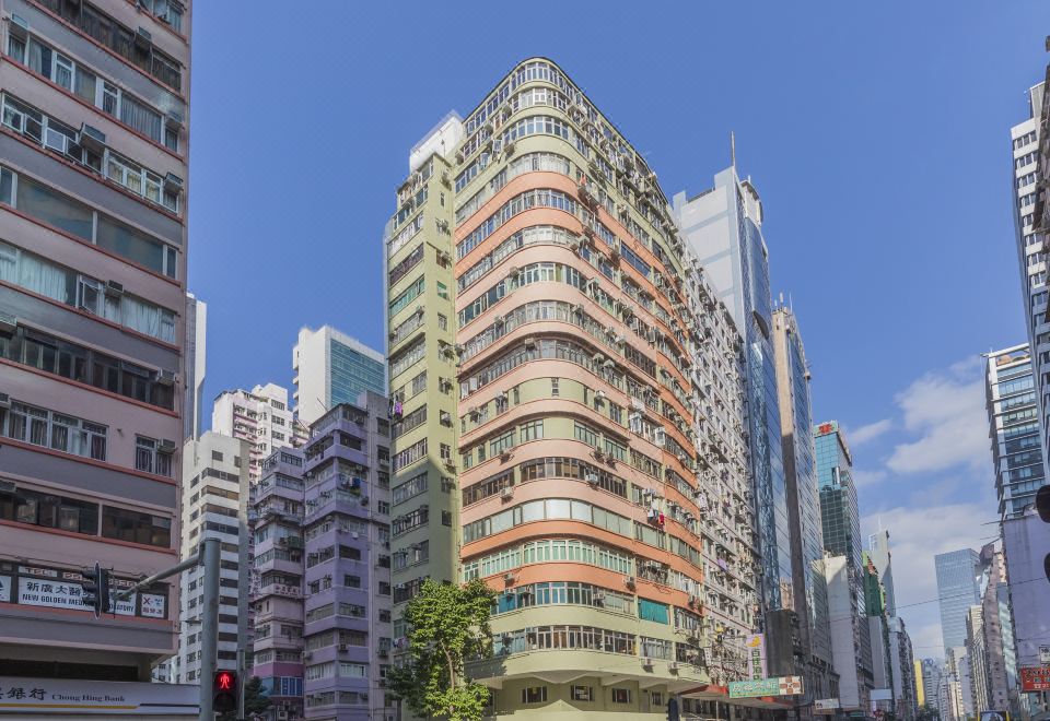 An intersection in a city with tall buildings and people walking on the sidewalk at Check Inn HK