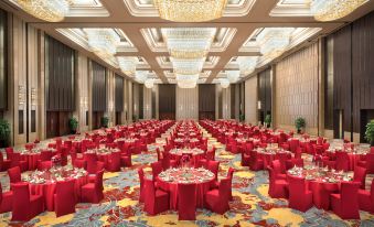 A spacious ballroom is elegantly arranged with red chairs and tables for an upcoming event at Shangri-La Hotel, Yiwu