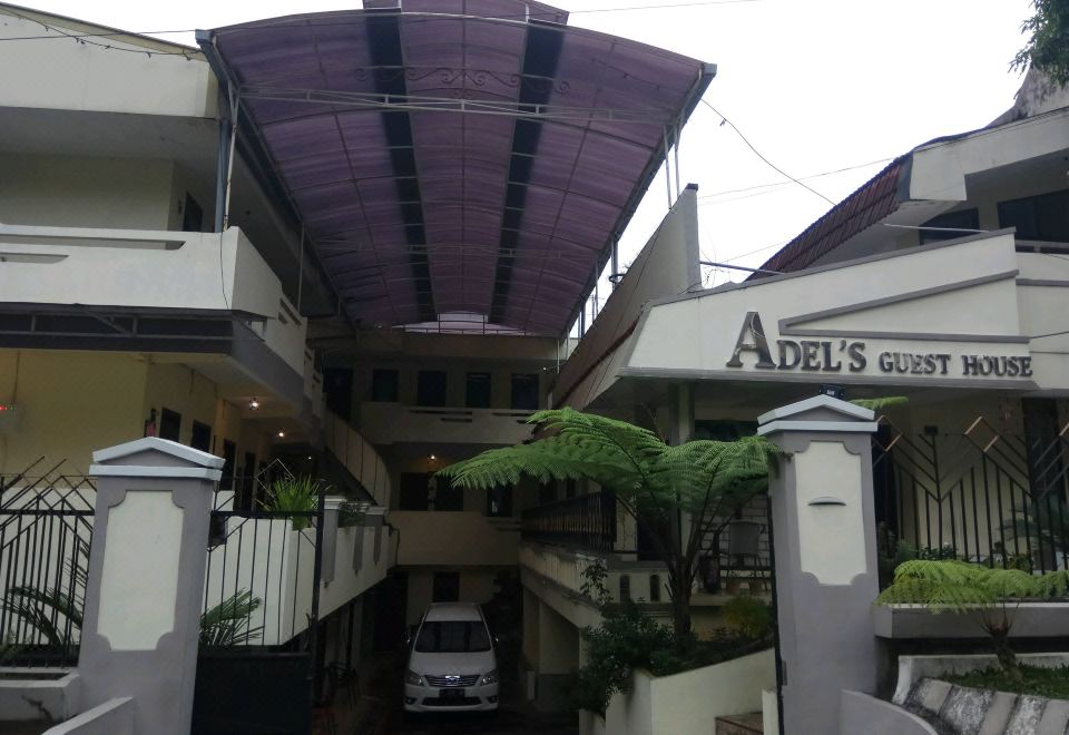 a large building with a purple roof , surrounded by greenery and a car parked outside at Adel Guest House
