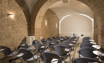 a conference room with rows of chairs arranged in a semicircle , and a podium at the front at Rome Times Hotel