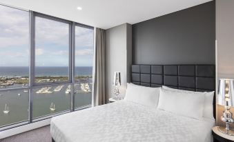 a bedroom with a large window overlooking the ocean and a bed with white sheets at Meriton Suites Southport