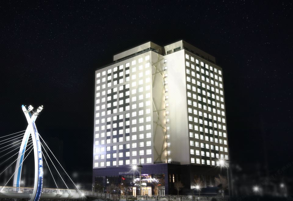 a tall white building lit up at night , with the surrounding area dark and illuminated at Am Hotel