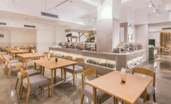 a restaurant with tables and chairs in the center, as well as other seating areas for customers at Ceramik Hotel (Foshan Lecong Furniture City)