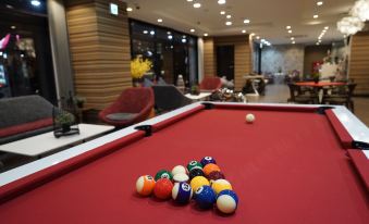 a red pool table with several pool balls on it , surrounded by chairs and other tables in a room at Hotel 88 Shinsaibashi