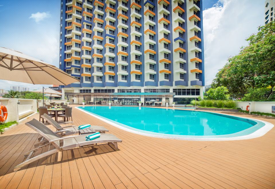 a large swimming pool surrounded by lounge chairs and umbrellas in front of a tall building at Oakwood Hotel and Residence Kuala Lumpur
