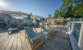 a wooden deck with blue and white lounge chairs , an umbrella , and a view of the ocean at Resort de Paskani