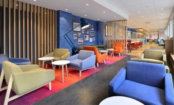 a modern lounge area with colorful furniture , including couches and chairs , arranged around tables and benches at Travelodge Sleaford