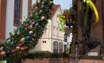 a christmas tree decorated with colorful ornaments in front of a building , creating a festive atmosphere at LUDWIGS